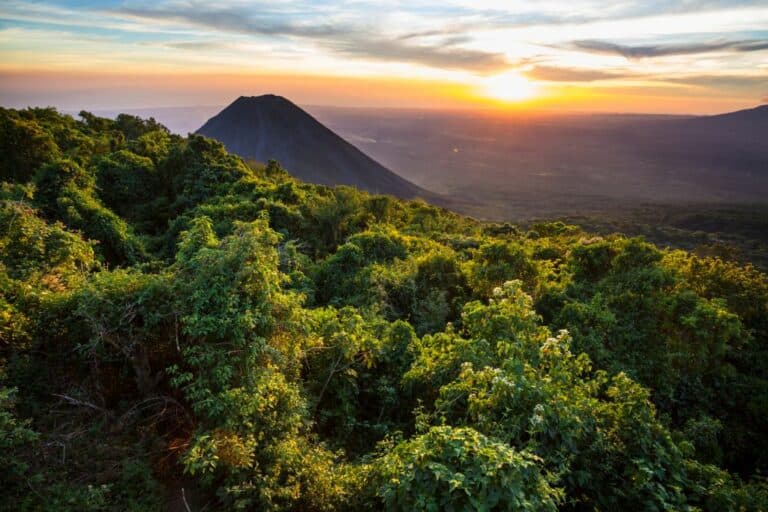 A stunning volcano in Cerro Verde National Park, El Salvador, showcases its majestic beauty as the vibrant colors of the sunset paint the sky, creating a breathtaking scene for solo female travelers to admire