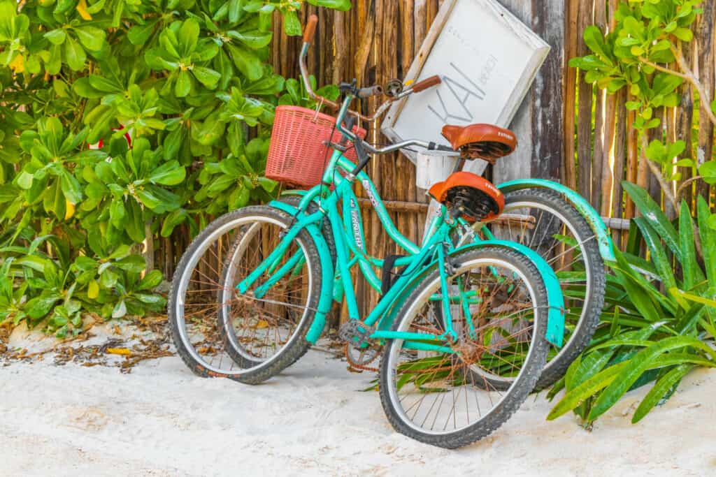 Tulum Mexico Turquoise bikes bicycles at the amazing and beautiful caribbean coast and beach panorama view with turquoise water people and huts of Tulum in Quintana Roo Mexico.